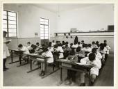 Professor e alunos no interior de uma sala de aula da Escola Primária Conde Ferreira.